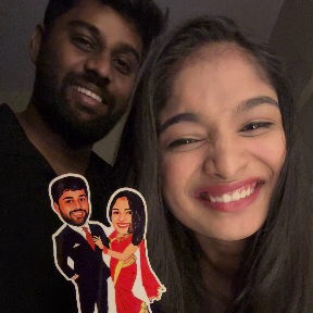 Two people holding a small wooden cutout with cartoon characters and text.